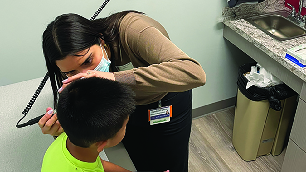 Carolina Carrillo M'25 examines a young patient in an exam room at the SMART Plus Clinic. 