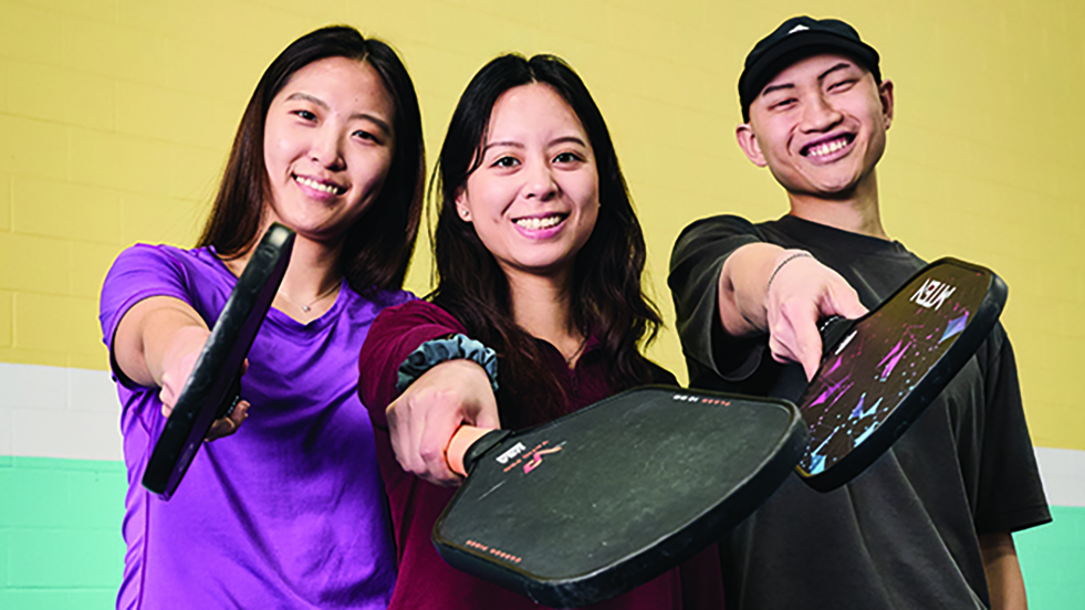 three people with pickleball racquets