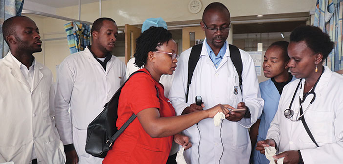 TECH SAVVY: Grace Wanjiku (in red shirt) demonstrates a smartphone-connected, portable ultrasound to ICU physicians at Kenyatta National Hospital in Nairobi in April. Photo by Shirley Wu, MD.