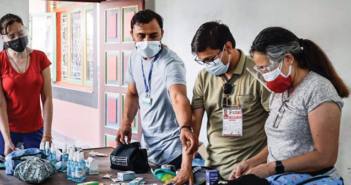 Ramu Kharel, second from left, and other volunteers assemble home isolation kits for COVID patients in Nepal.