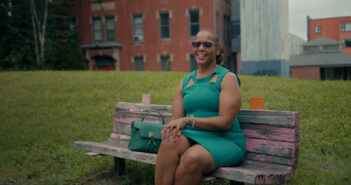 Rochelle Ives, administrative program manager and executive assistant to the vice president of Dining Services, sits on a bench while he is interviewed outside of the John Hope Settlement House in Providence.